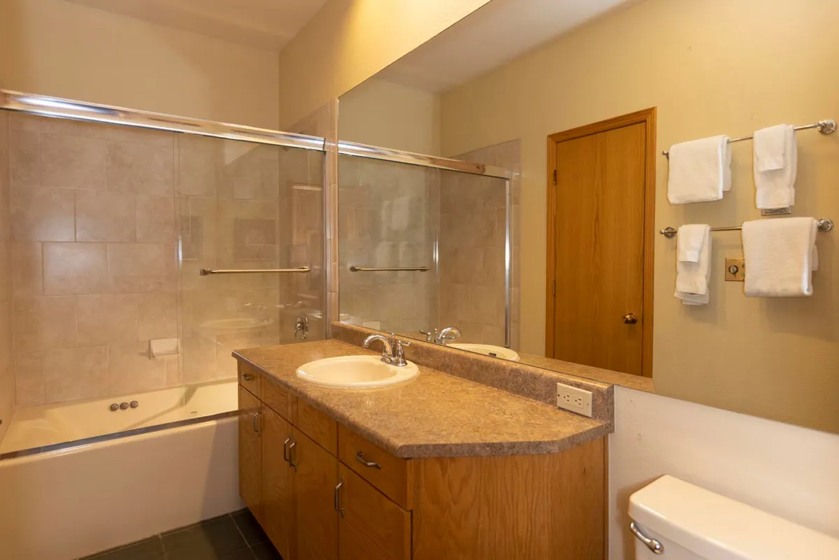 A modern bathroom featuring a soaking bathtub, expansive vanity with mirror, and neatly arranged towels. The space feels clean, calm, and tailored for self-care and relaxation after a day of mountain adventures.